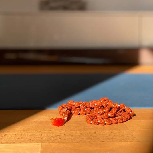 Mala-Gebetskette auf Holzuntergrund im Yoga Studio – Symbol für Meditation und Achtsamkeit