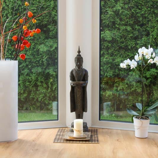 Buddha-Figur mit Kerze im lichtdurchfluteten Yoga-Raum bei JAZUYOGA