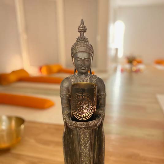 Buddha-Figur mit Kerze im Yoga Studio – Symbol für Achtsamkeit und innere Ruhe