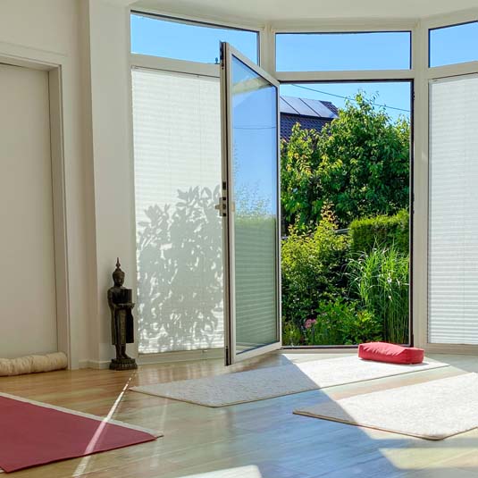 Ausblick vom Yoga Studio in den grünen Garten – ruhige Umgebung für Yogapraxis